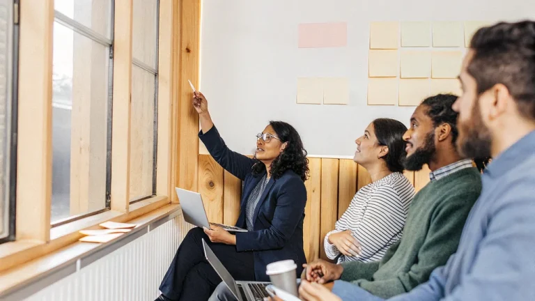 Training design team mapping the stages of an ADDIE instructional design plan on sticky notes in a meeting room