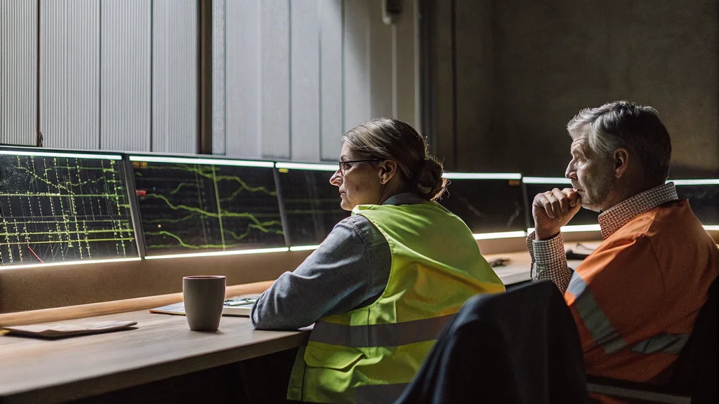 Grid control room operators monitoring network displays while weighing controlled islanding against load shedding
