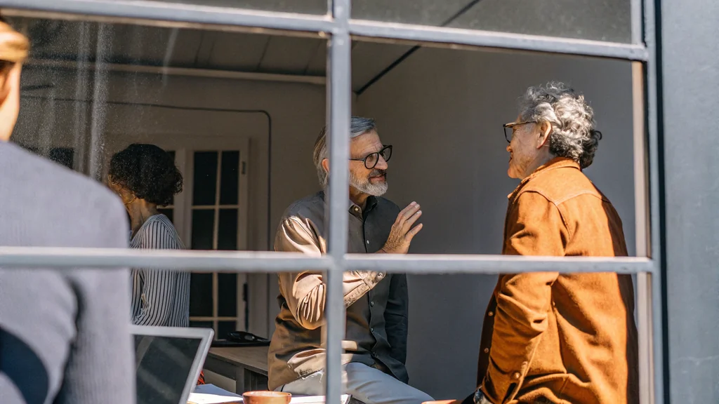 Executives having a difficult conversation in a glass-walled office