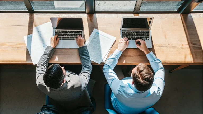 Project managers reviewing reports together at a sunlit office table