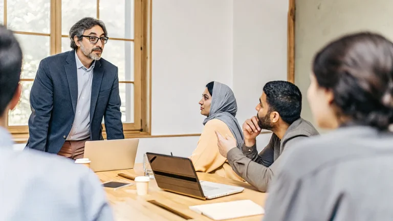 Manager speaking with calm confidence to an attentive team around a meeting table