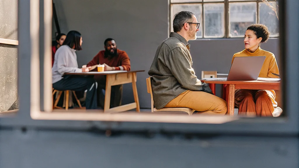 Manager and employee discussing performance goals over a laptop during a one-to-one review in an office